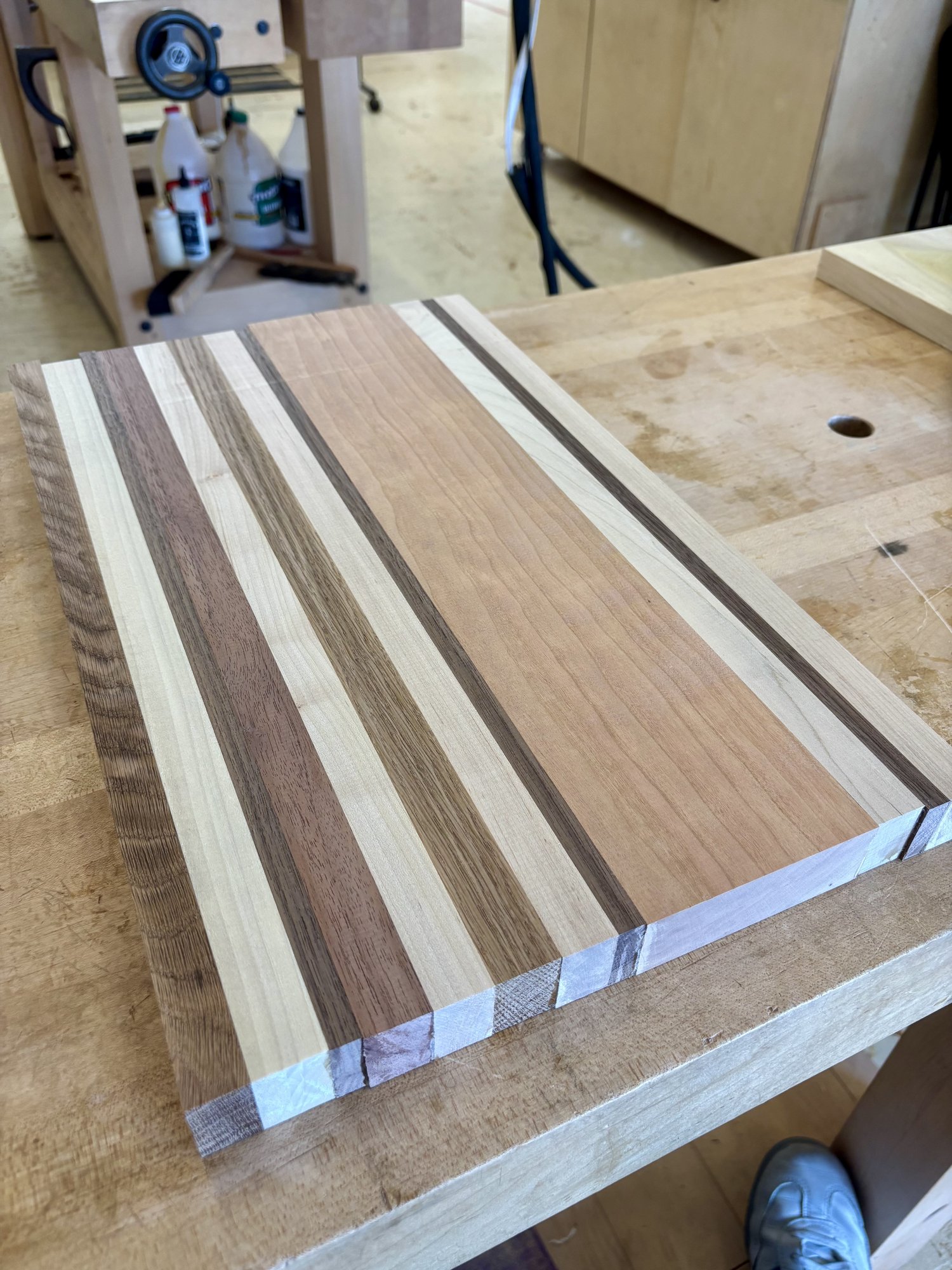 Out of the clamps and planed flat. The pattern is now legible — varied stripe widths, a wider cherry section near the right edge as a quiet focal point.