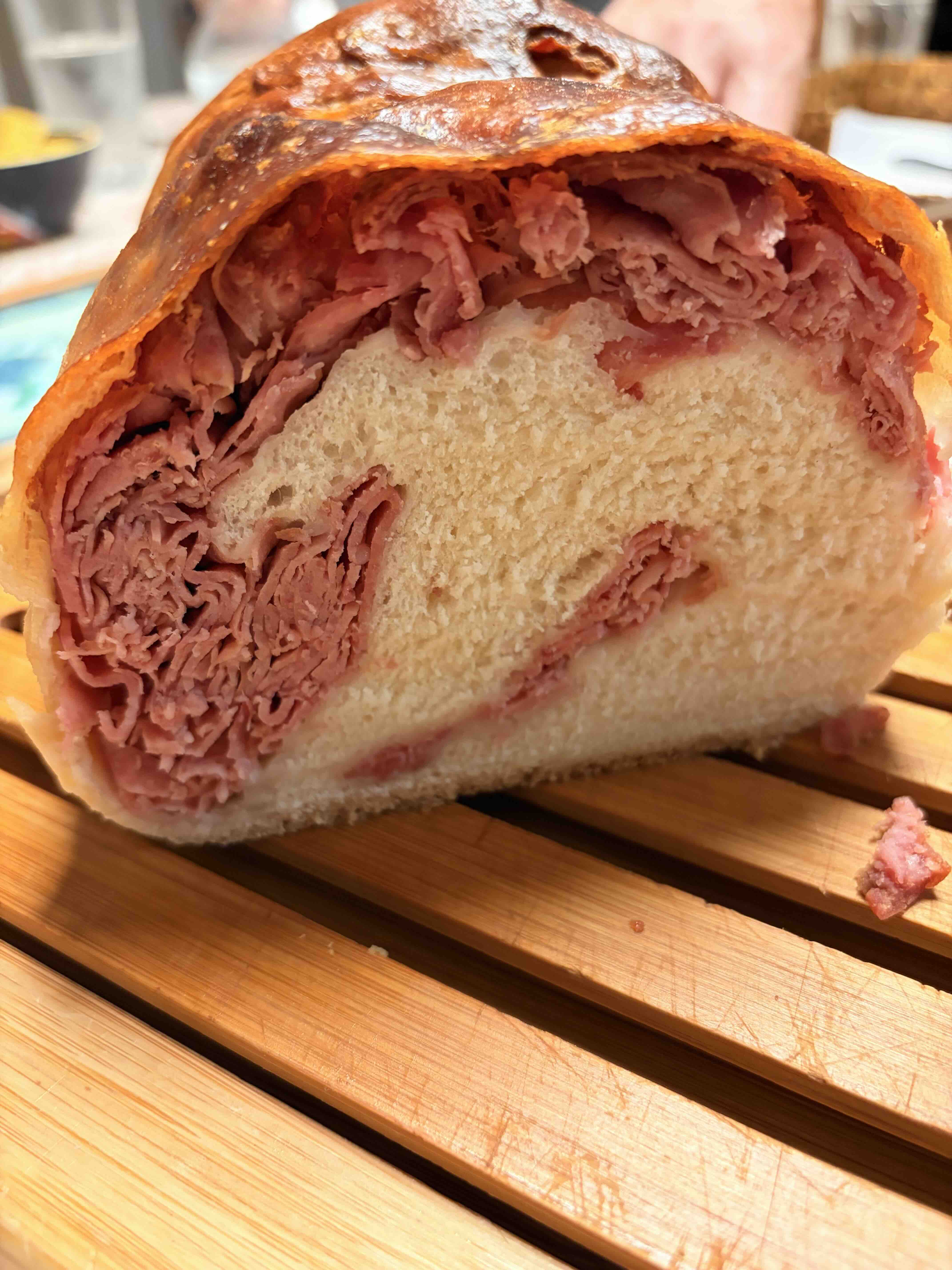 A loaf of Italian Calabrese bread on a table, deeply colored crust, open-crumb structure visible at the cut edge.